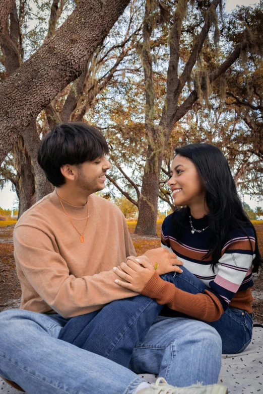 man and woman sitting under trees smiling at each other