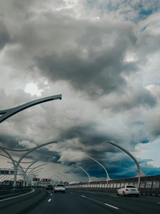 a view from the driver's seat of a vehicle driving past clouds above