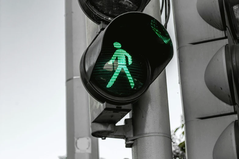 a green pedestrian sign attached to a traffic light