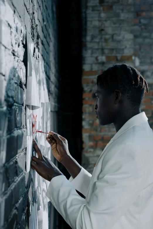 a man painting on a white board next to a brick wall