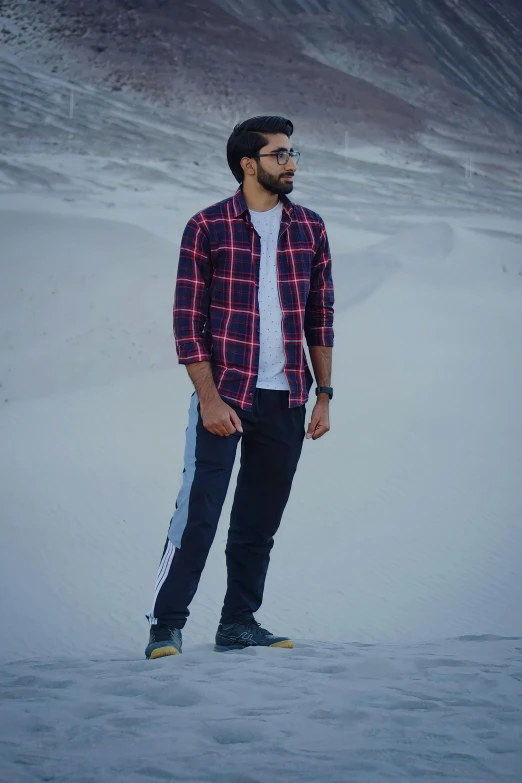 a man standing in the snow in front of a mountain