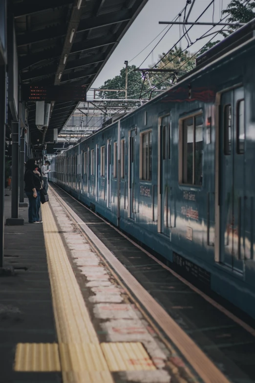 people standing at a train station waiting to board the train