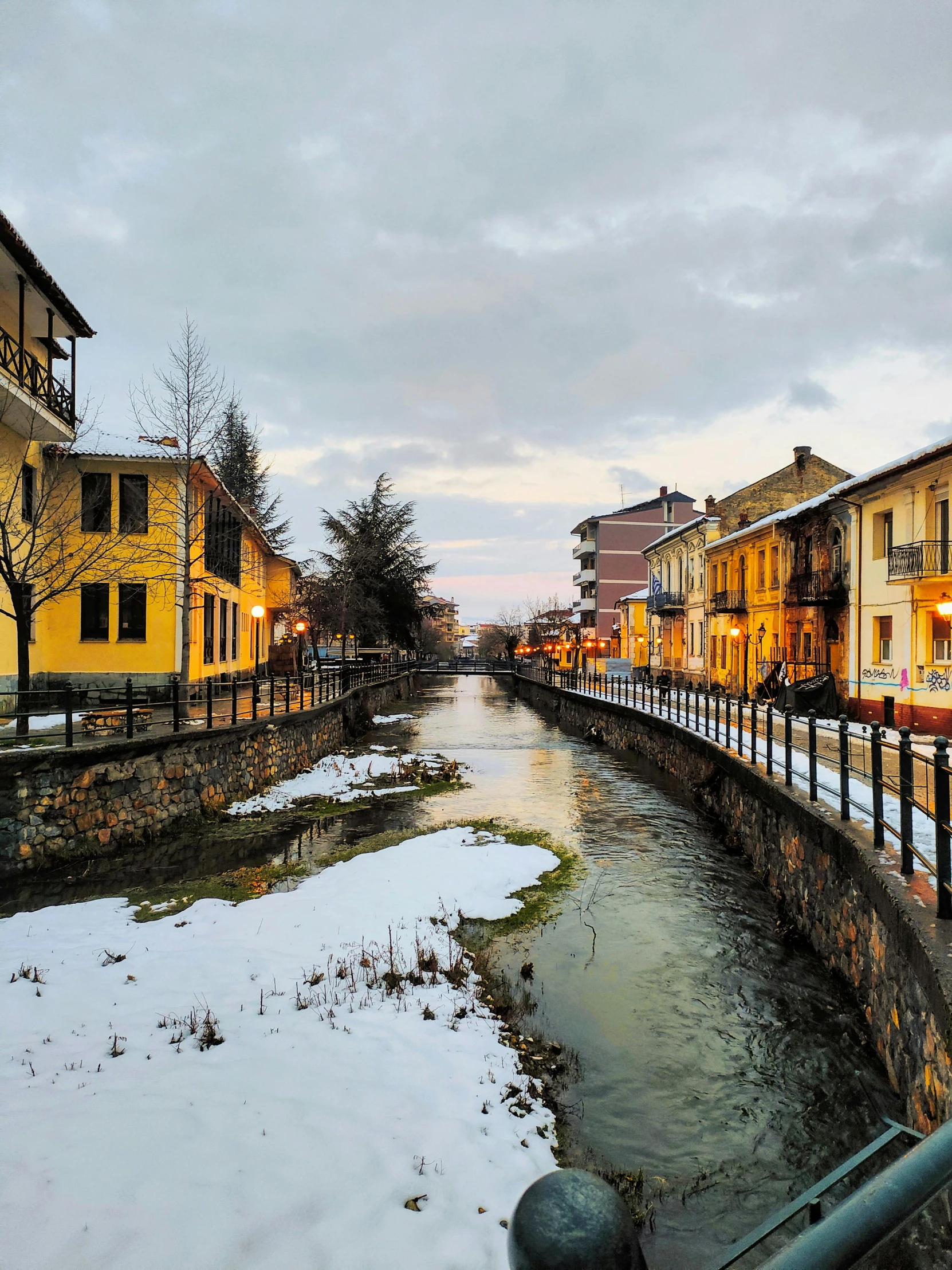 a river flowing between two building with lamps on them