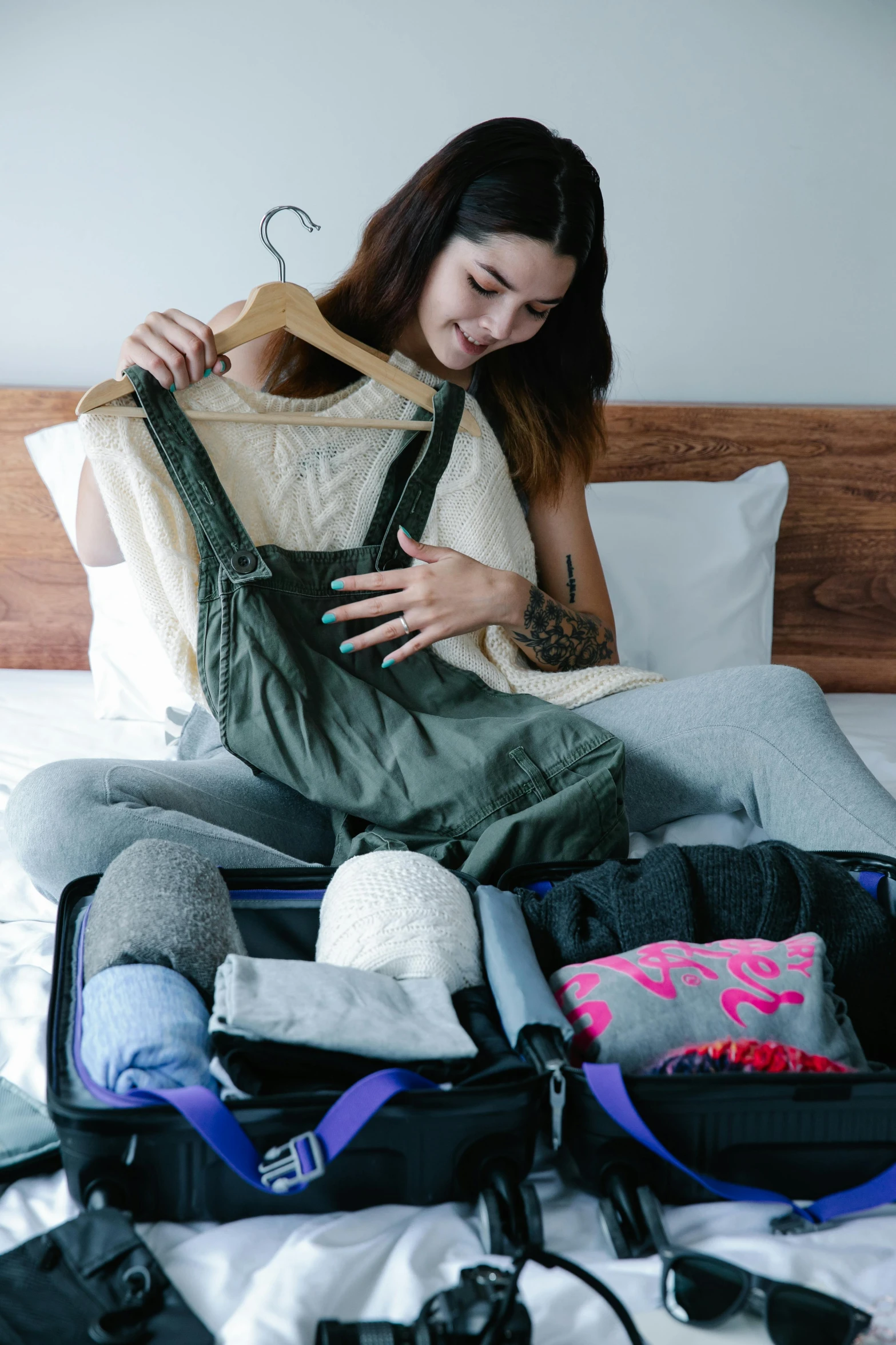 a girl sitting on a bed holding some clothes