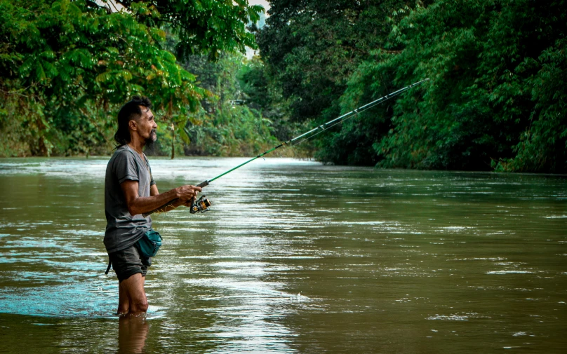 man holding a fishing rod in the middle of a river