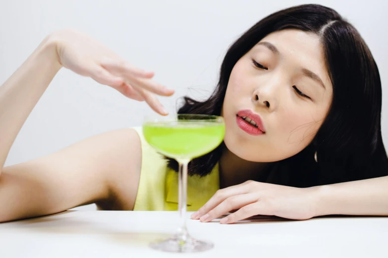 woman looking at green drink in a martini glass