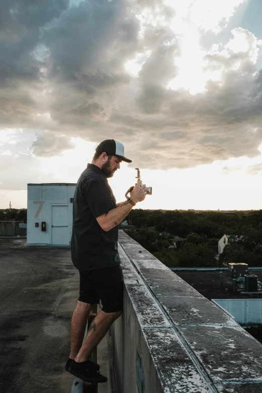 a man standing on a ledge looking at a remote controller