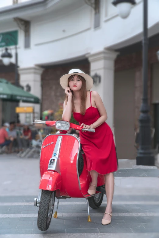 a woman wearing a red dress sits on a red scooter