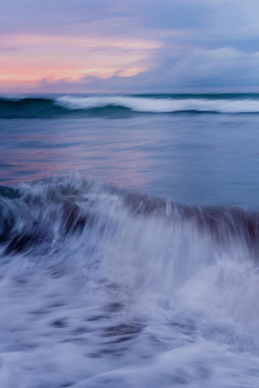 some water waves crashing to shore under a cloudy sky