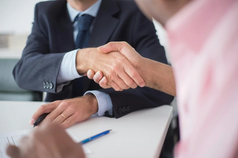 two people wearing suits holding hands at a desk