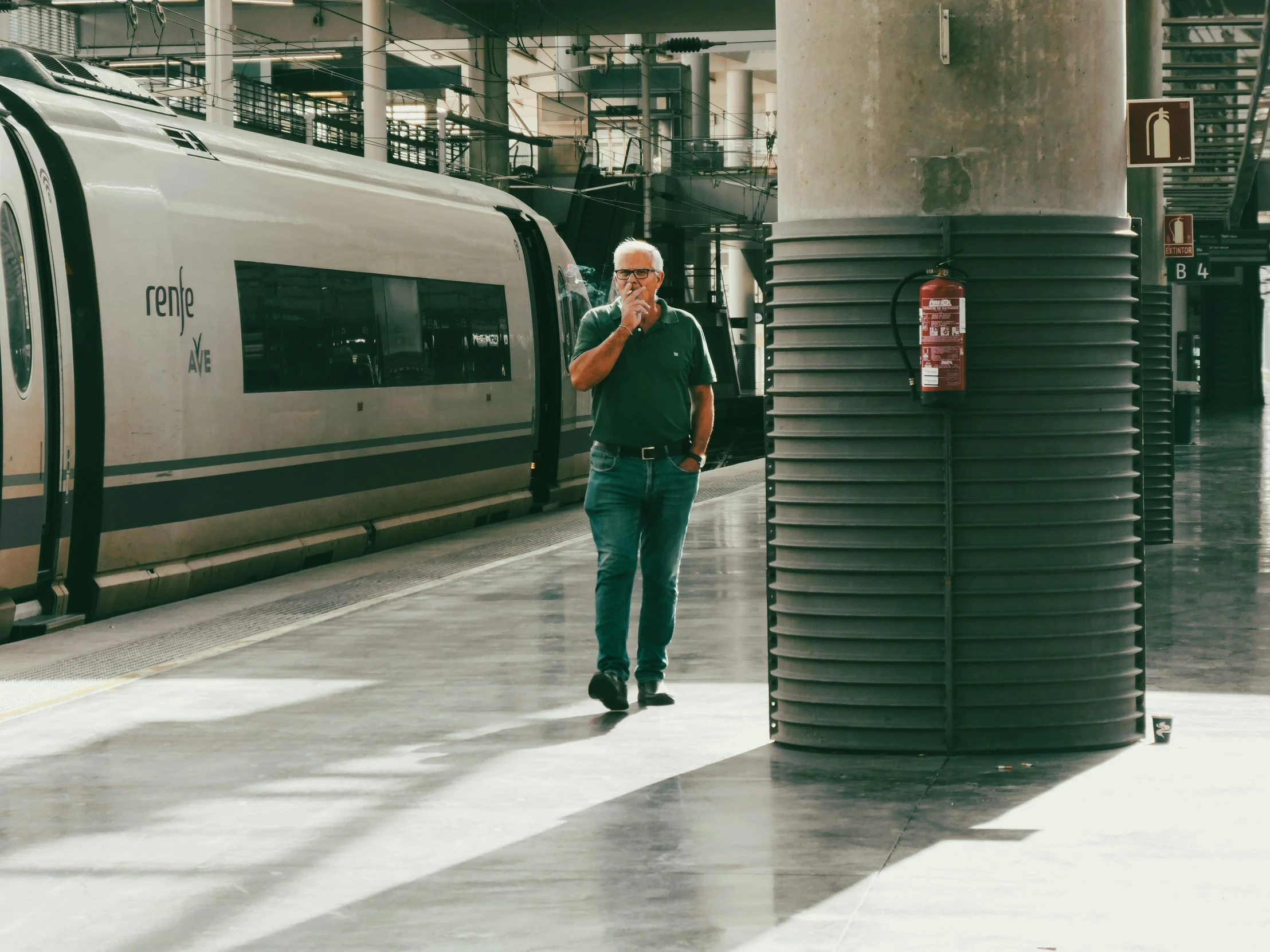 man standing at a train station while looking down