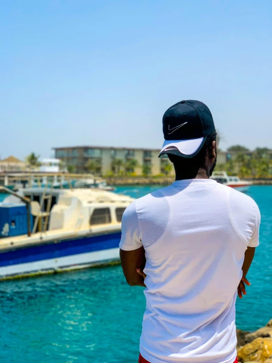 a man stands on the edge of the water looking at the boats