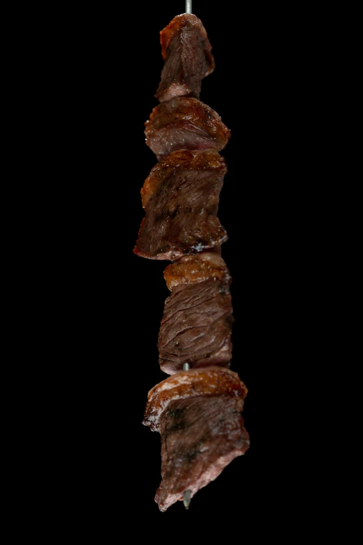 there are several pieces of beef hanging from a grill