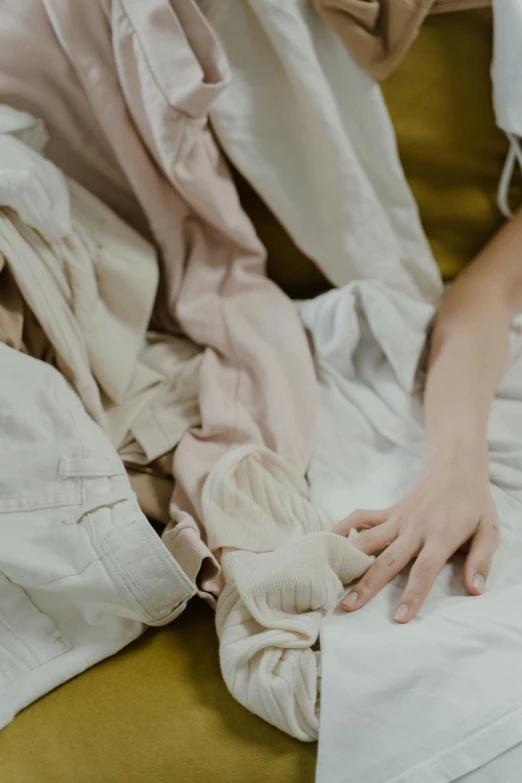 a person wearing white is reaching up to the bed sheets