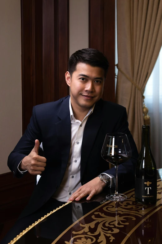 a man sits with a glass of wine in his hand