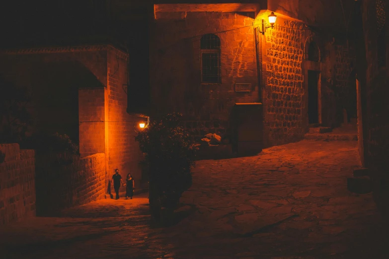 two people standing at night next to a building with a lamp on