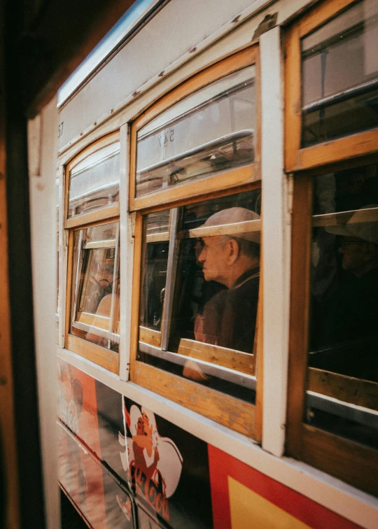 an old man sitting in the seat of a train looking out the window