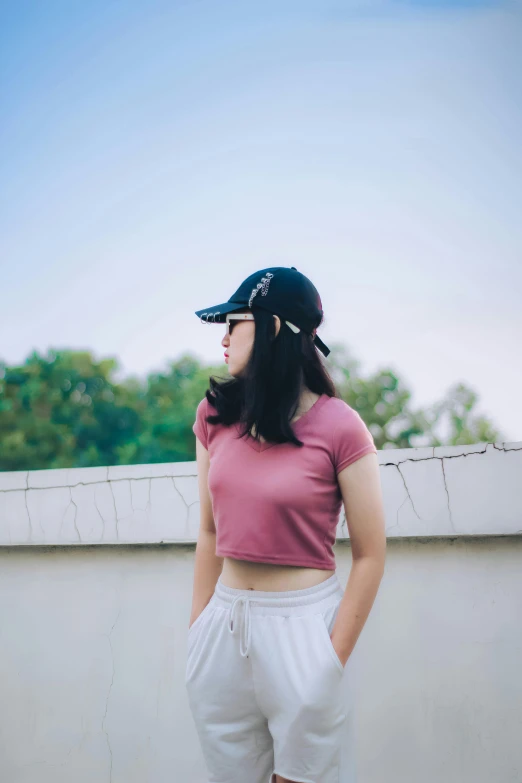 a woman in a pink shirt standing near a wall