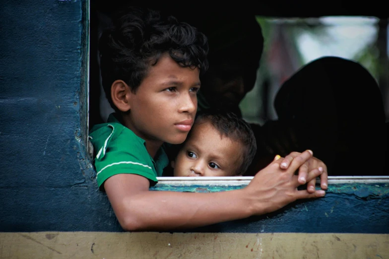 two children looking out the window of their home