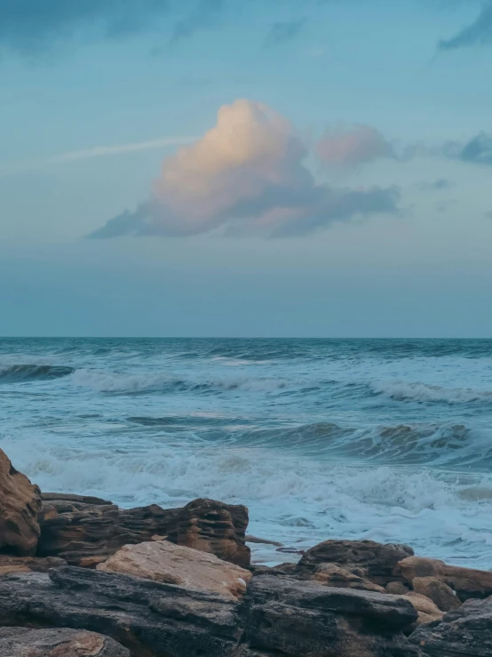 a person stands on rocks in front of the ocean