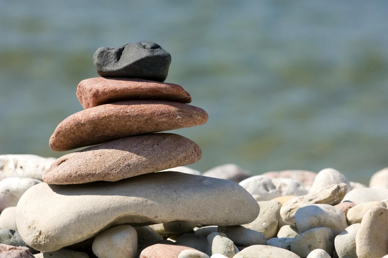 pile of rocks on the sand with a rock in the middle of it