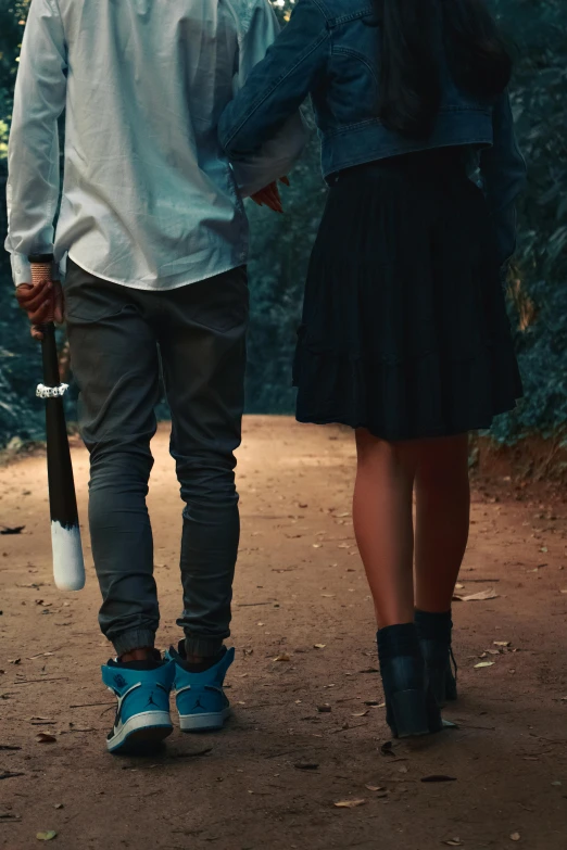 a couple is walking down the dirt road holding their umbrella