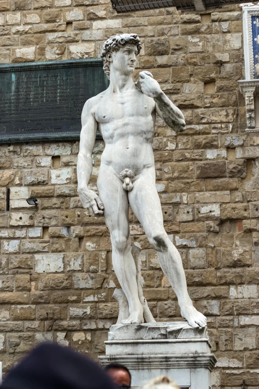 a statue that is standing up next to a brick wall