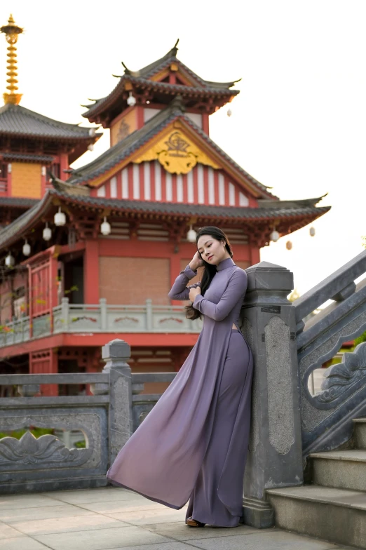 woman leaning on railing and using her cell phone near asian temple