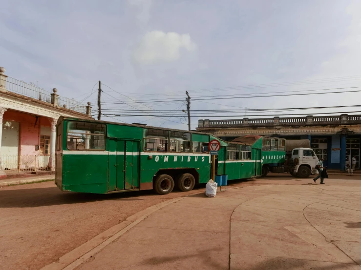 a green bus sitting parked on the side of the road