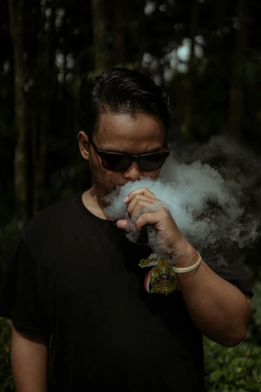 a man with sunglasses smokes an electronic cigarette