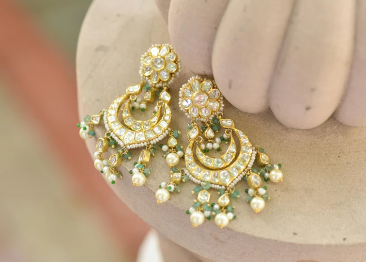 two sets of gold jewelry with pearls and green stones