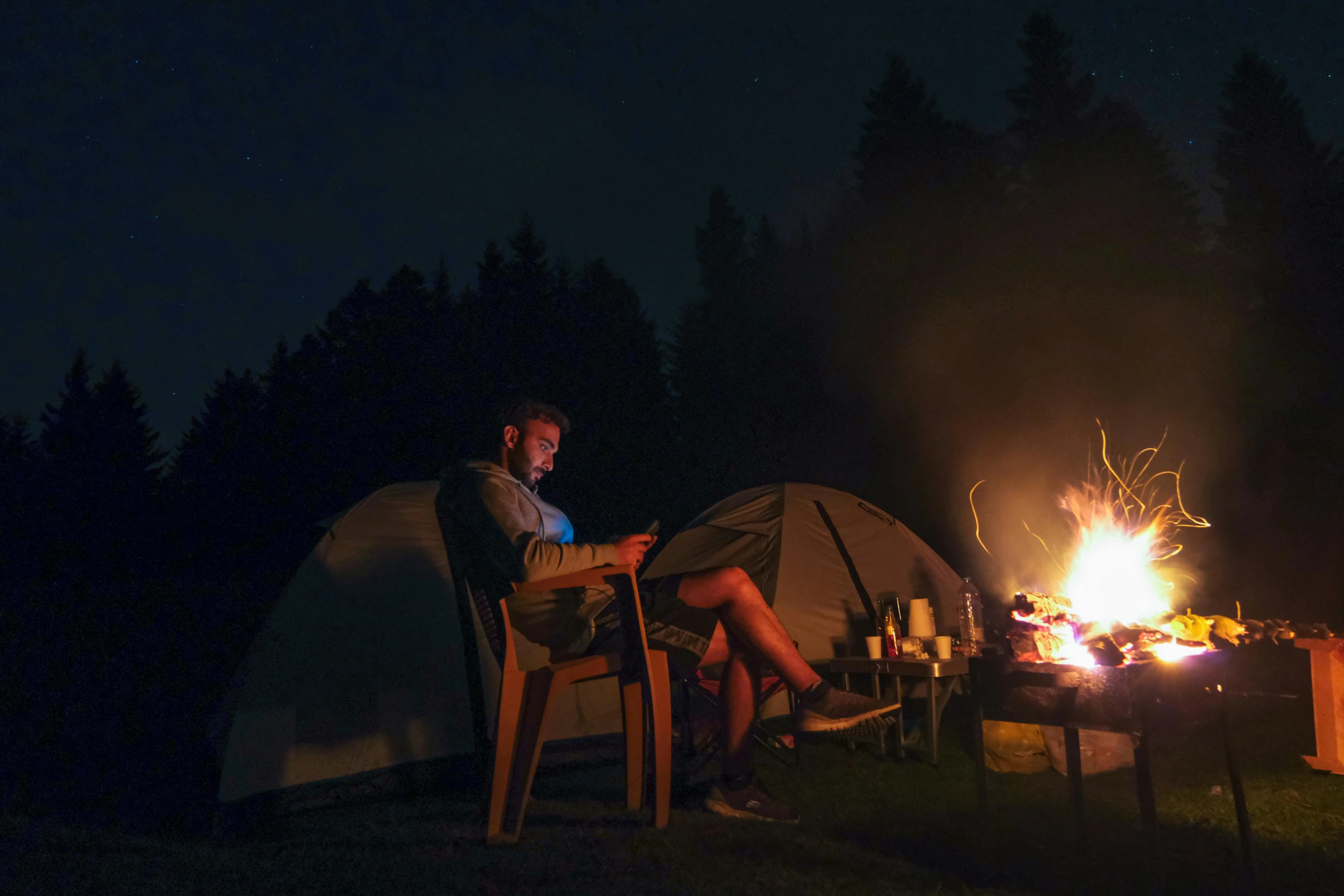 a man is setting up his camp fire by himself