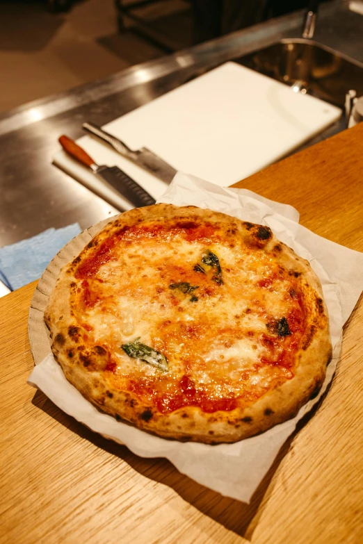 a cheese pizza is sitting on paper and some knives