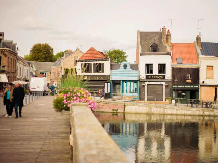 a woman walks down a canal walk with colorful buildings