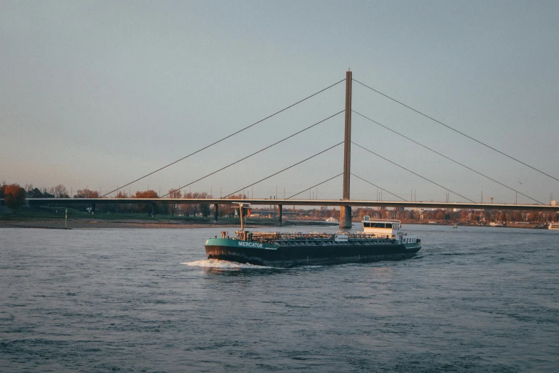 a boat floating on top of a lake under a bridge