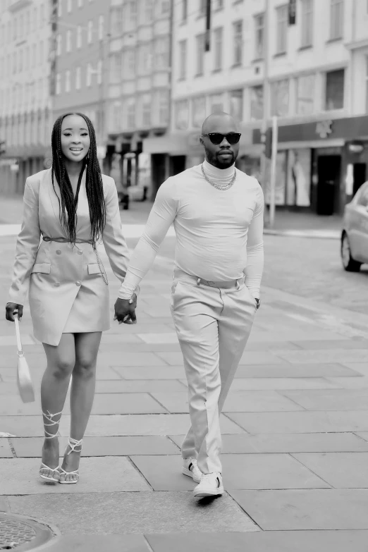 black woman in a white suit holding hands with a man in a pink dress