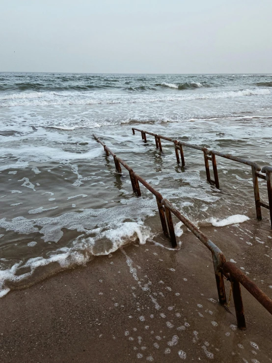 rusty posts sticking out of the sand into the ocean