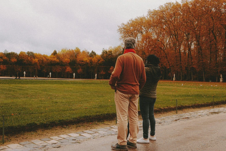 two people stand by each other in a park