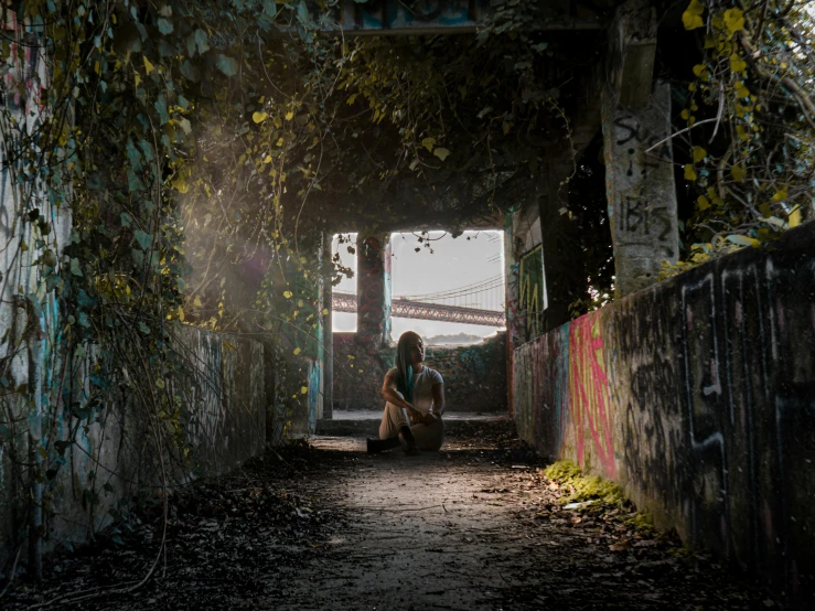 a person sits outside and plays in a tunnel