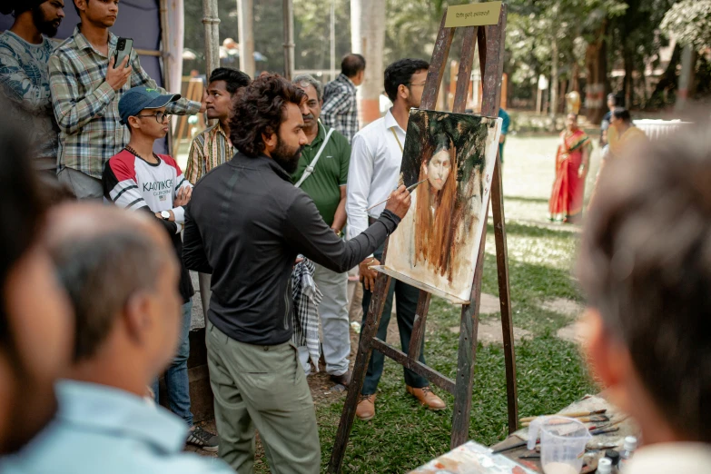 a man standing in front of a easel near a group of people