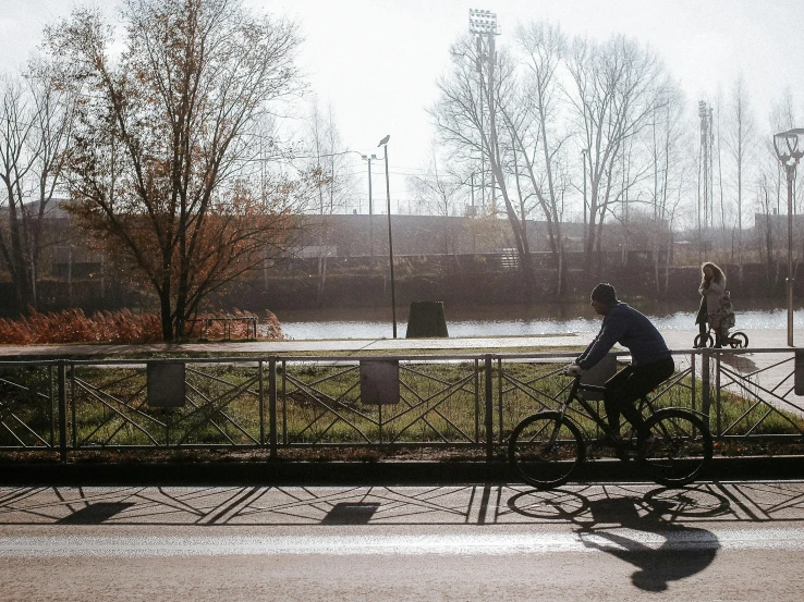 two bicyclists ride past a bridge in the rain