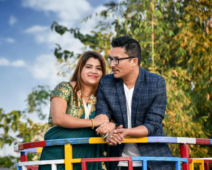 a couple of people that are leaning on a fence