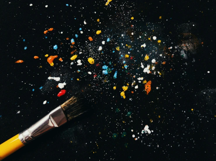 a small paintbrush filled with confetti sitting on a black table