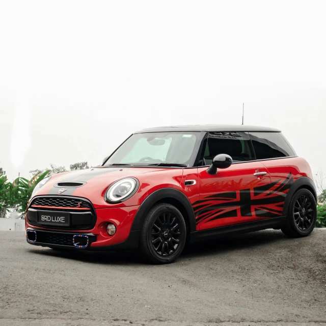 a mini cooper in a driveway, painted red and black