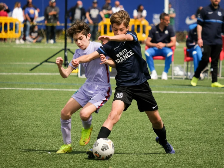 two boys are playing soccer on a field