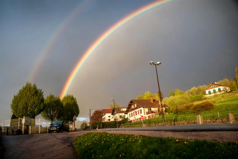 a double rainbow appears over homes on a road