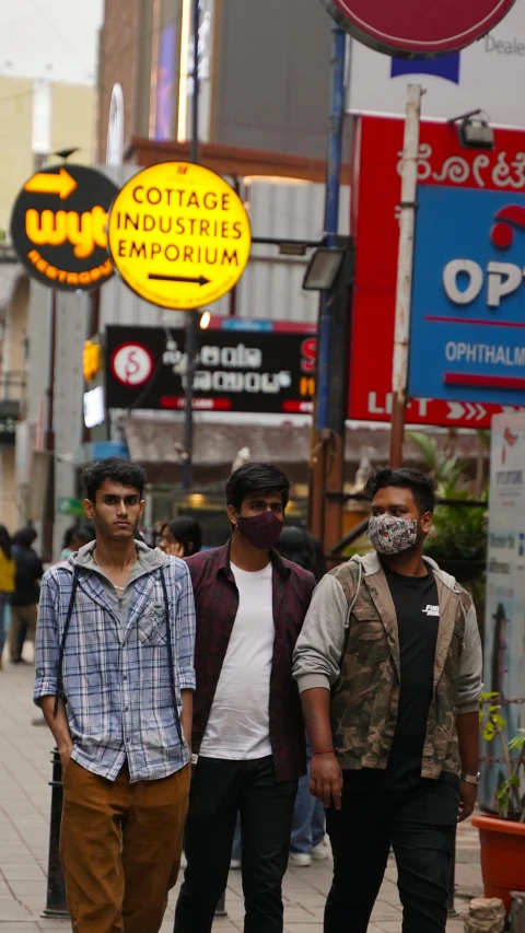 three guys walking down the sidewalk by shops