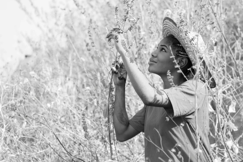 a young lady wearing straw hat standing in tall grass