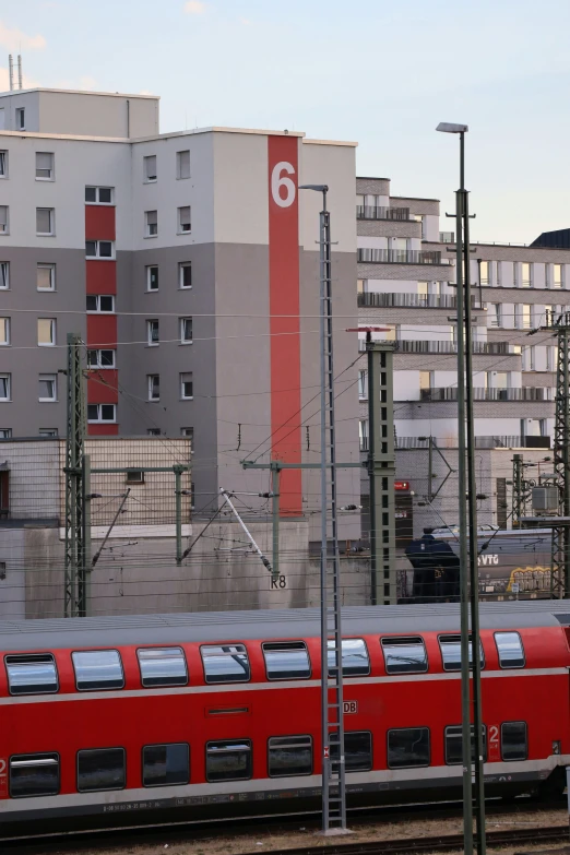 a red train traveling down tracks next to tall buildings