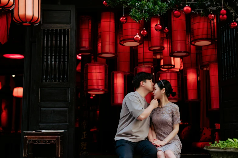 the man and woman are kissing outside of the lanterns